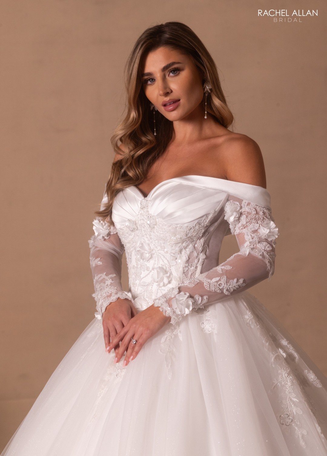 1.	Rachel Allan Style RB6180 off-the-shoulder ball gown with floral applique, glitter tulle layers, and beaded long sleeves in ivory satin